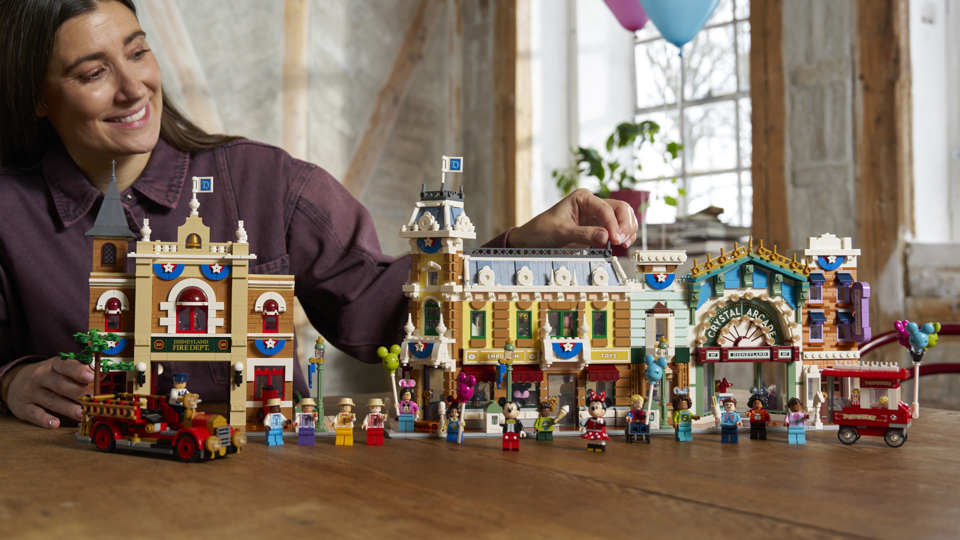 A woman smiles while placing a piece on Lego Main Street USA