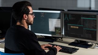 man working on Linux OS across two screens