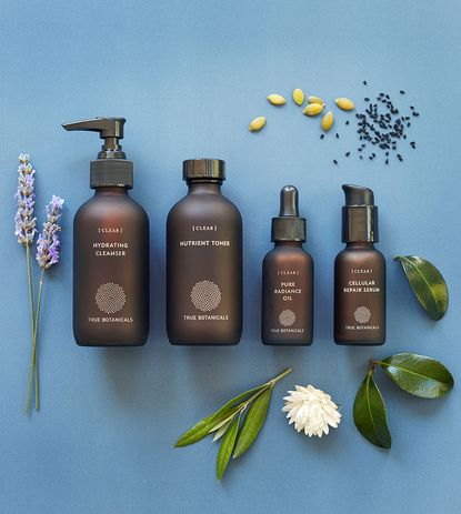 True Botanicals products in brown bottles on a blue background