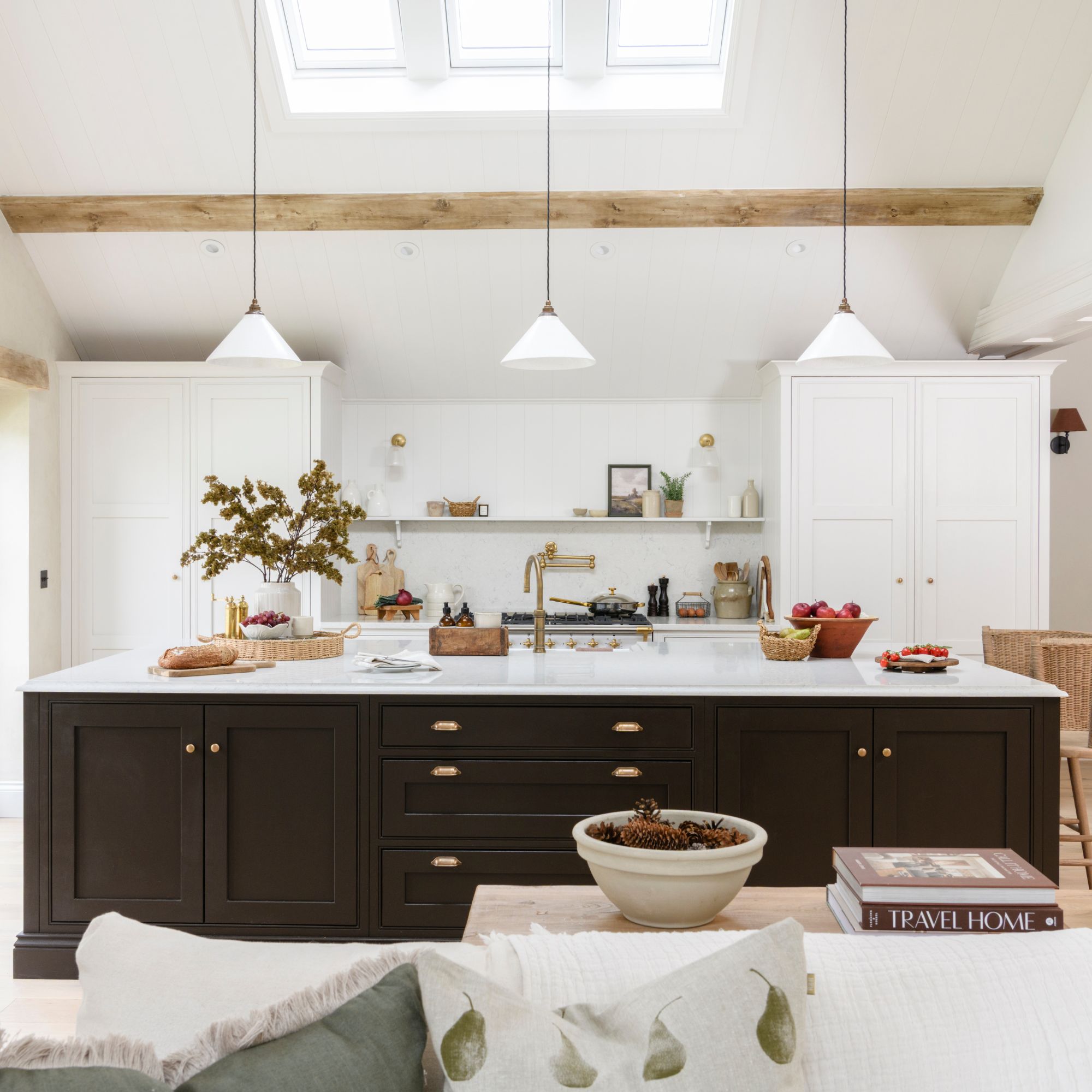 White painted kitchen with white cabinets against the back wall and a large kitchen island with black cabinets and a white worktop