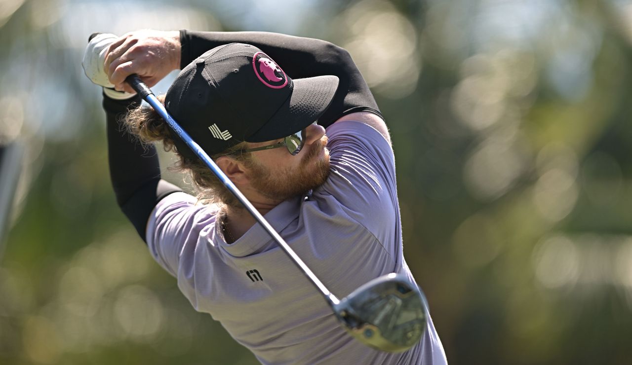 Kieran Vincent strikes a fairway wood and watches the flight of it 