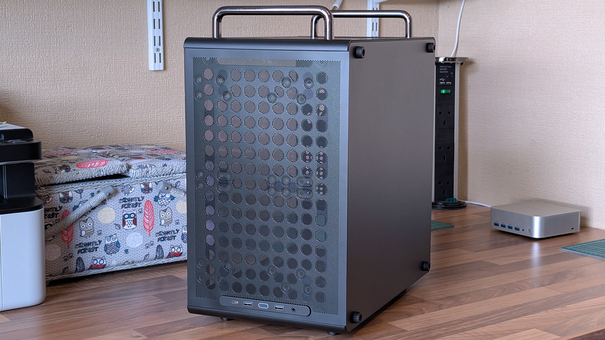 The front of a Cooler Master Qube 340 case features a large mesh panel, visible internal components, and top handles, with front I/O ports along the upper edge.