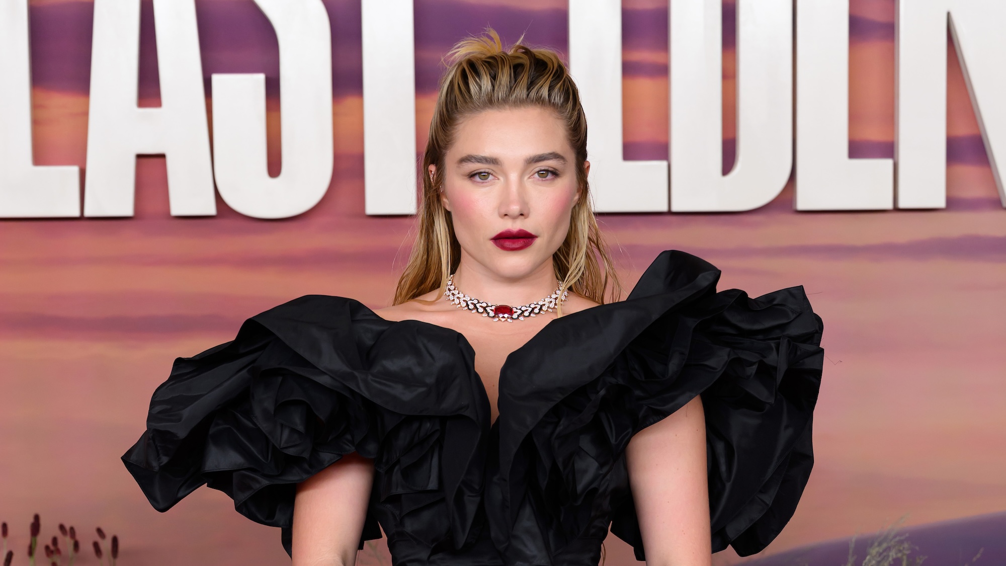 Florence Pugh wearing a black gown and bold jewelry while posing at the "East Of Eden" Screening at BAFTA