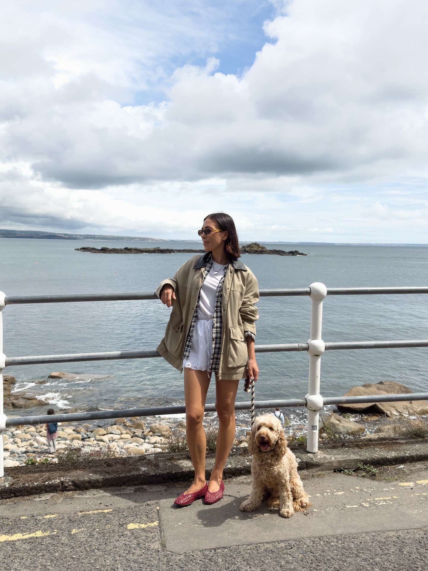 Jessica wears M&S flats with shorts and a jacket by the sea