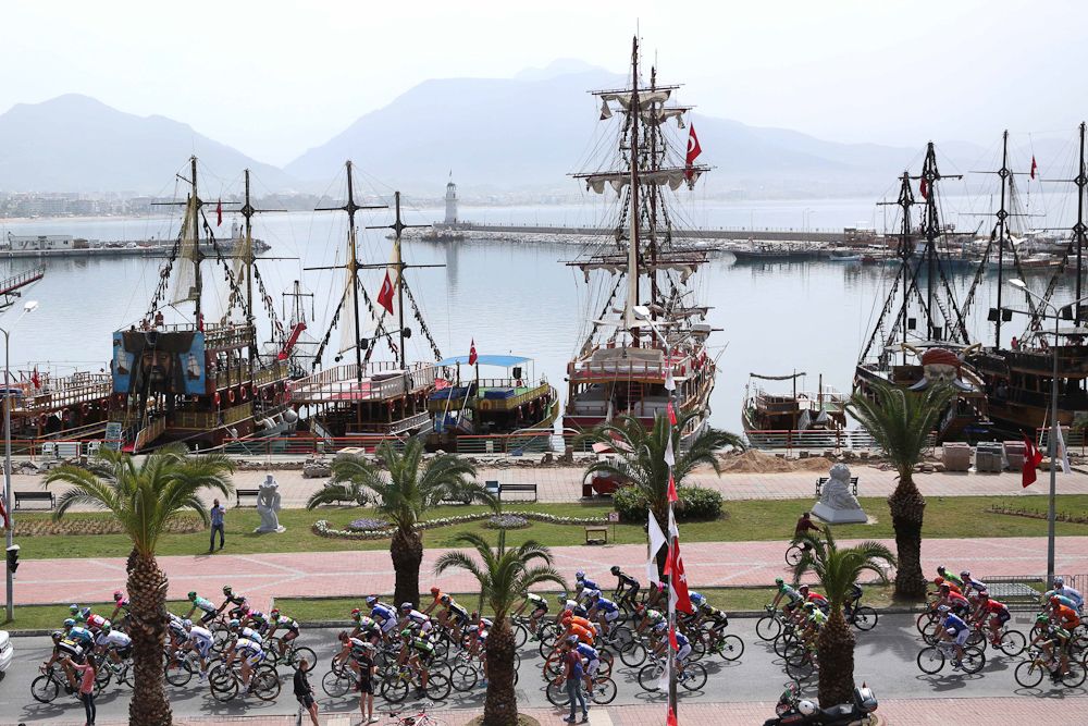 Tall ships float in the background as the peloton passes by.