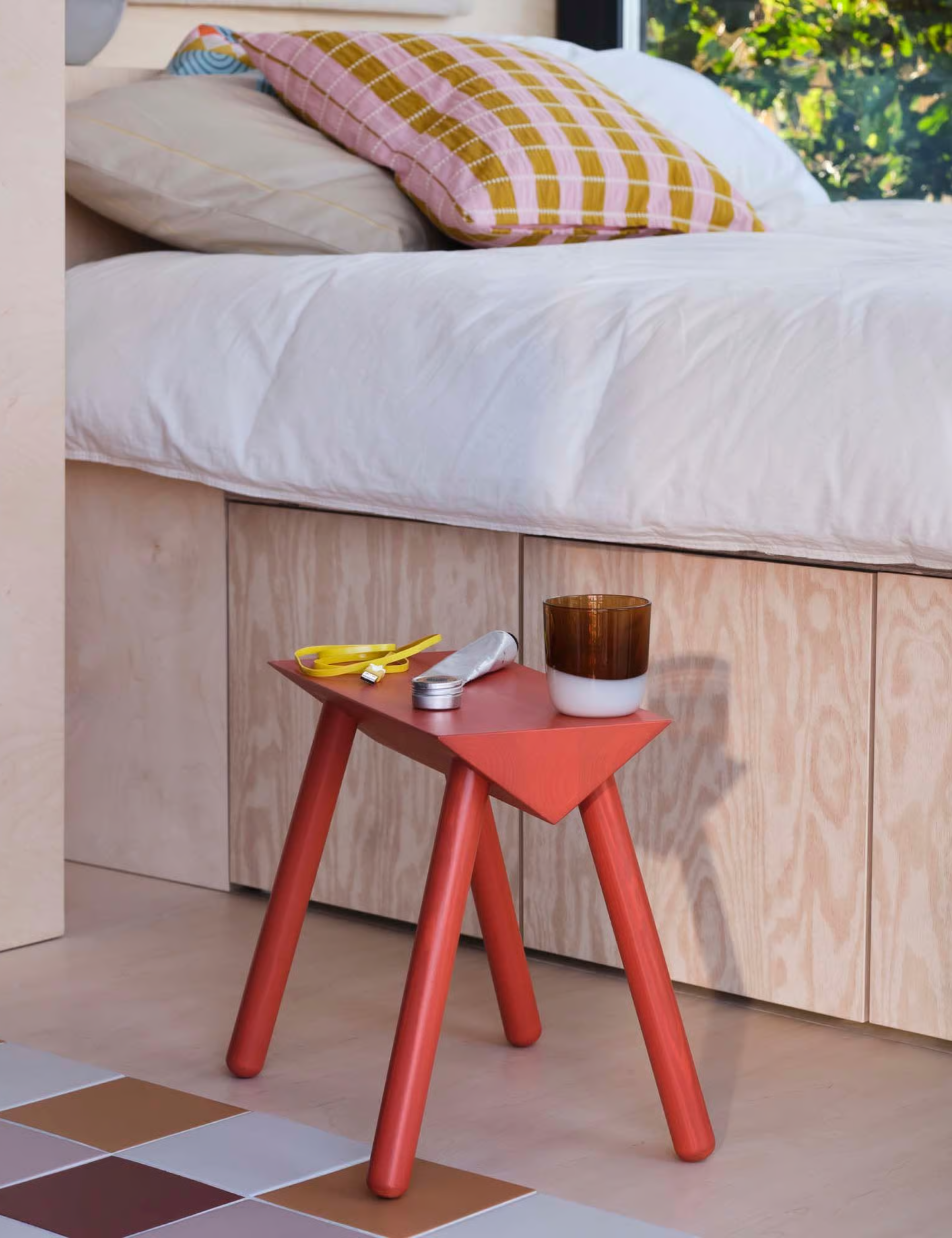 Colorful bedroom area featuring an angular red wooden wide table and patterned throw pillows