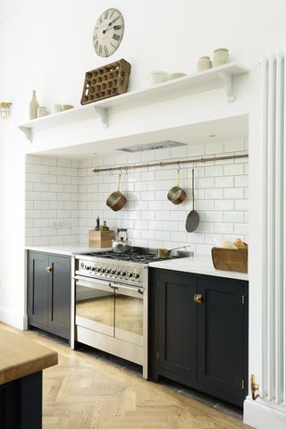 Black kitchen cabinetry with white metro tiles and light wooden effect flooring