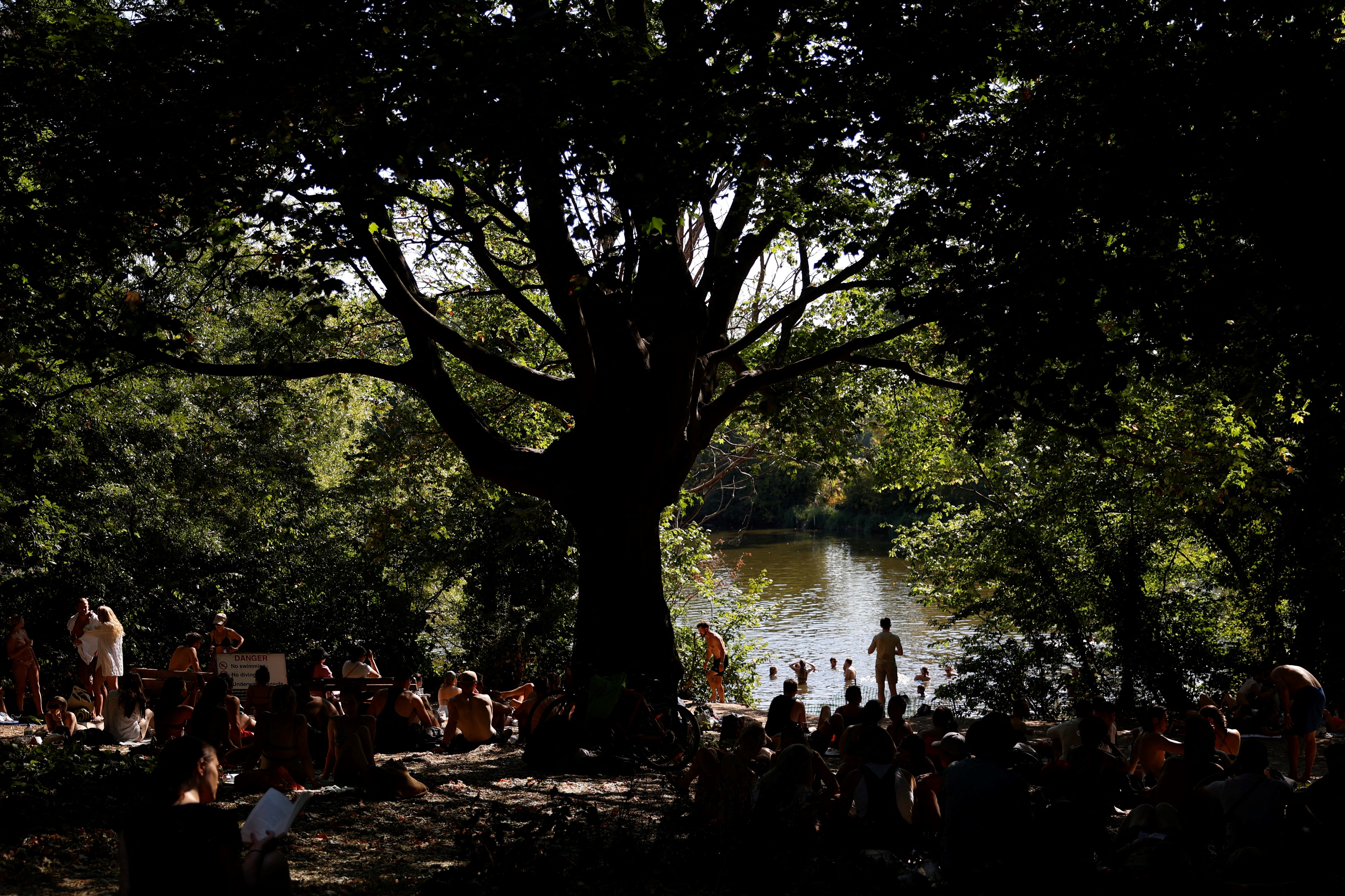 TOPSHOT - People have a swim on a pond in Hampstead Heath park to cool off from the heat, in London, on August 13, 2022. - The UK government on Friday officially declared a drought across swathes of England, following months of record low rainfall and unprecedented high temperatures in recent weeks.