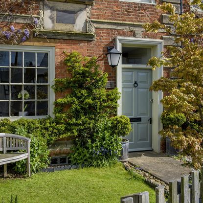 house exterior red brick wall blue door and plants