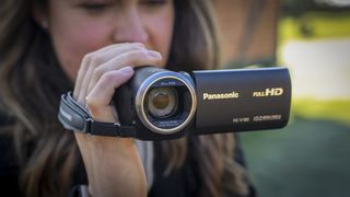 The Panasonic HC-V180 camcorder being held by a young woman