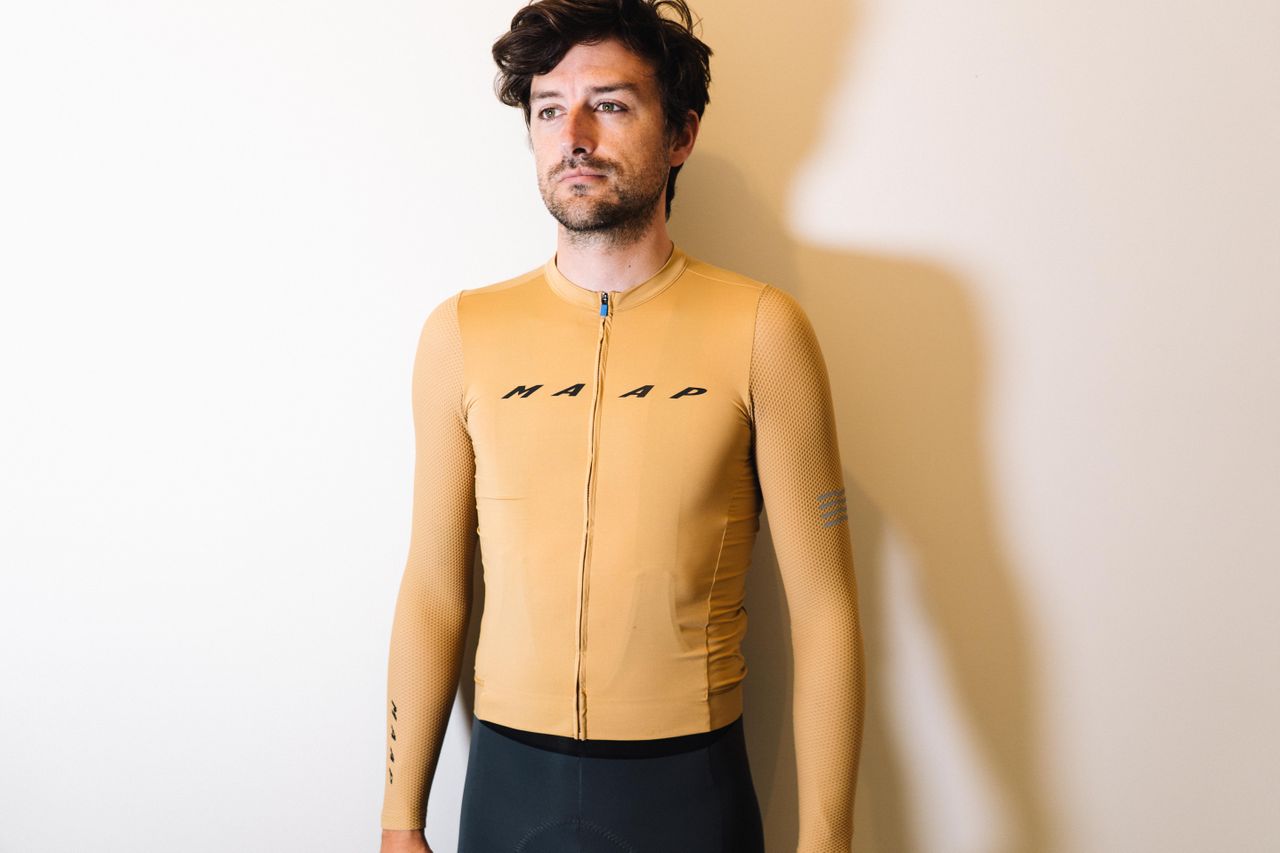 A white man in a tan jersey against a white wall