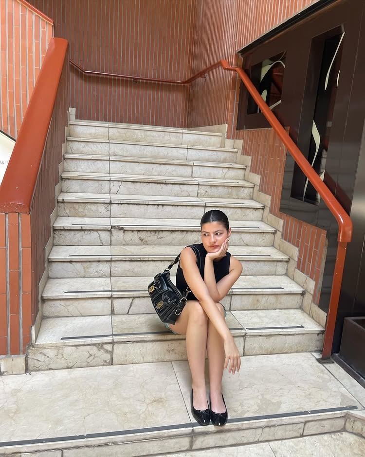 Taylor Creel in a chic outfit sitting on a marble staircase.
