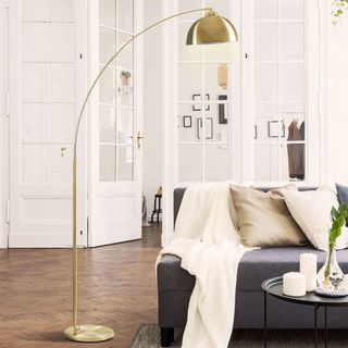 brass tall arched floor lamp in living room over sofa