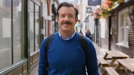Ted Lasso smiling as he walks down a British street in season 4 of his self-titled Apple TV show