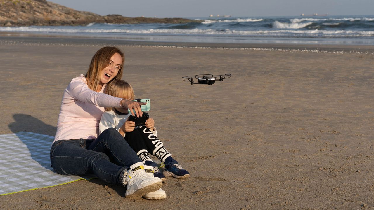 Woman and child flying the Potensic Elfin on a beach