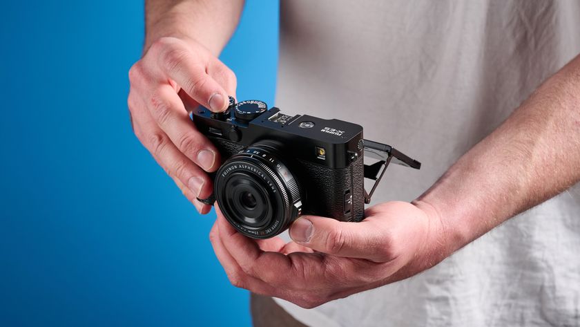 Fujifilm X-E5 in hand against a blue background