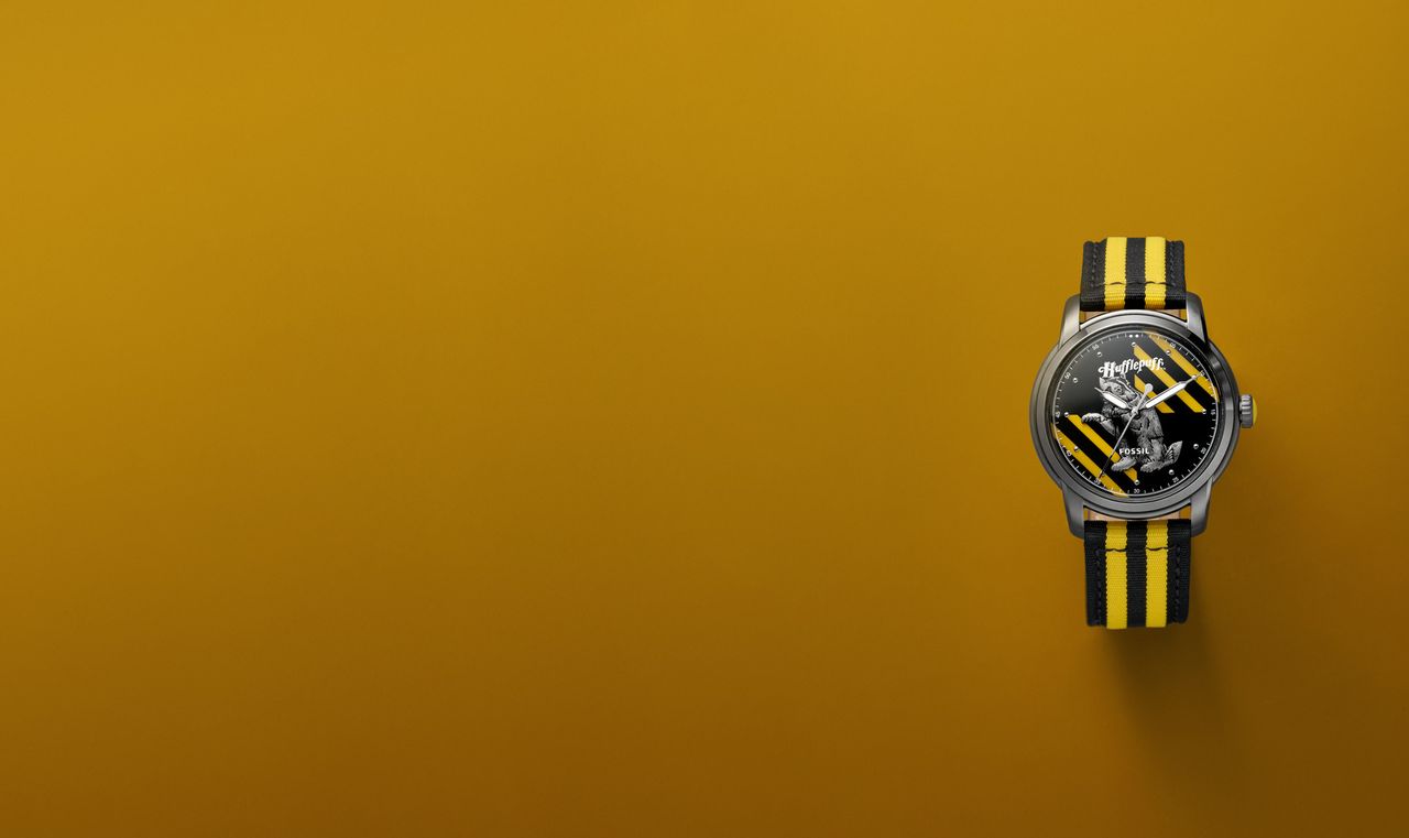 A Harry Potter x Fossil Nylon watch in the Hufflepuff design, on a yellow background
