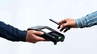 Image showing wireless payment terminal with a person holding a smartphone over it