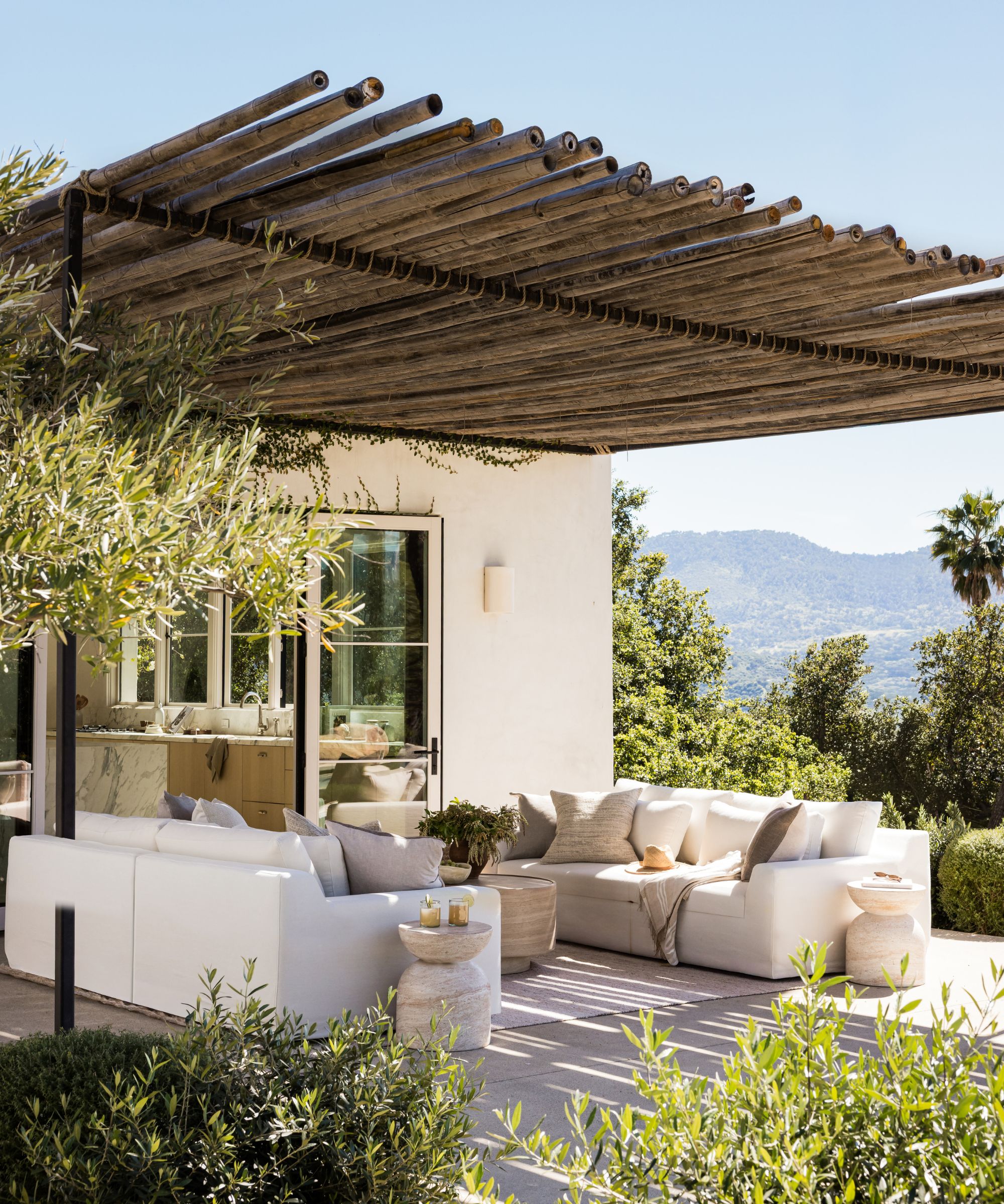 Neutral and organic outdoor living space with bamboo shade and olive trees