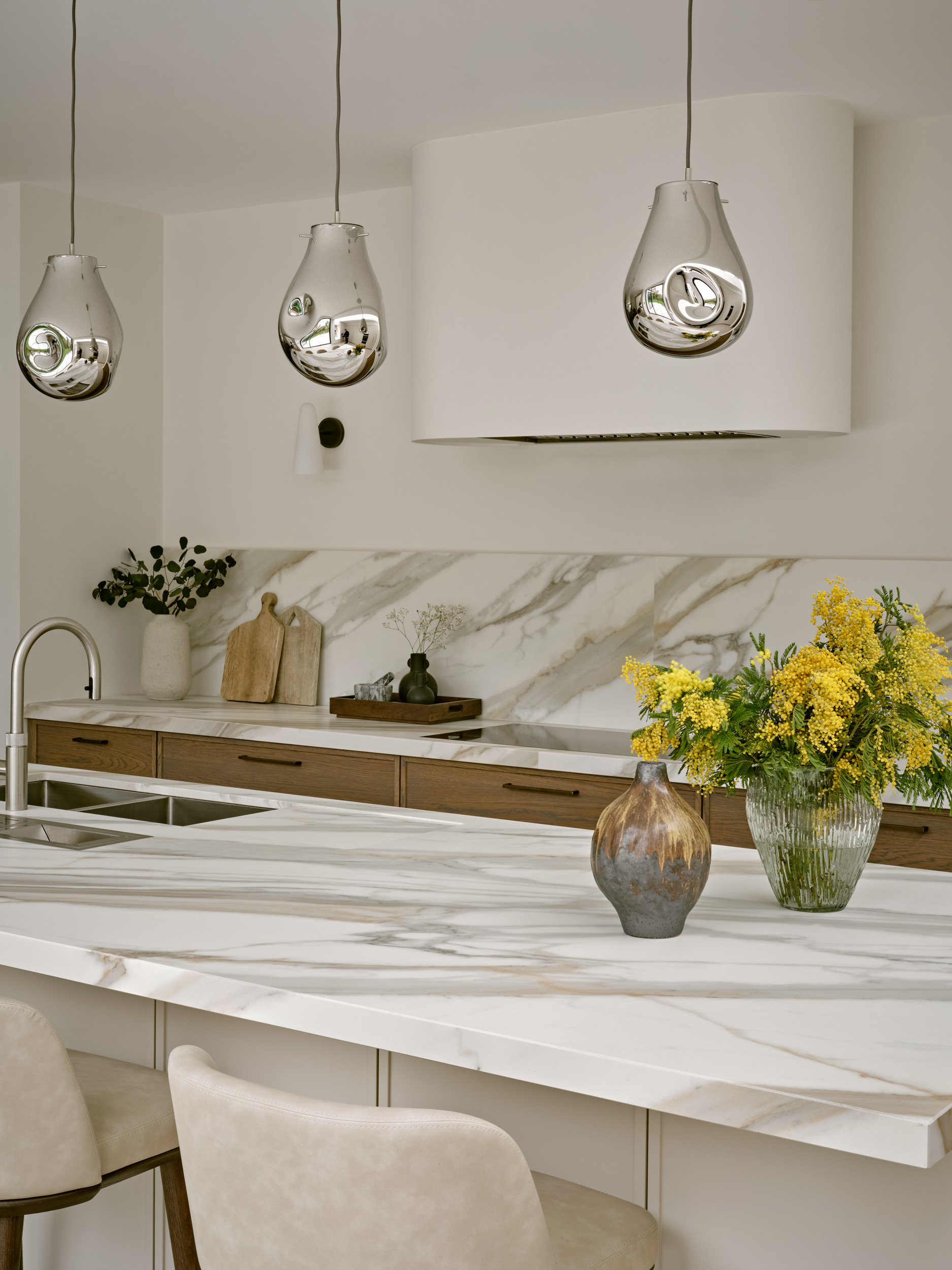 modern kitchen with kitchen island seating, silver pendant lights, and marble counters