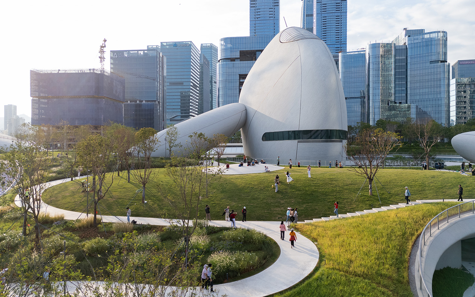view of MAD Shenzhen Bay Culture Square, all white volumes and curves in a green park
