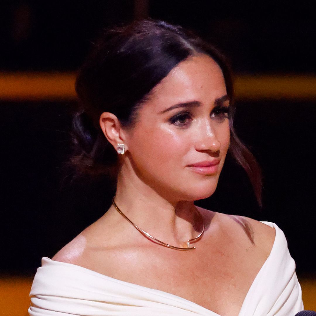 Meghan Markle looks tearful at an event while wearing a white top