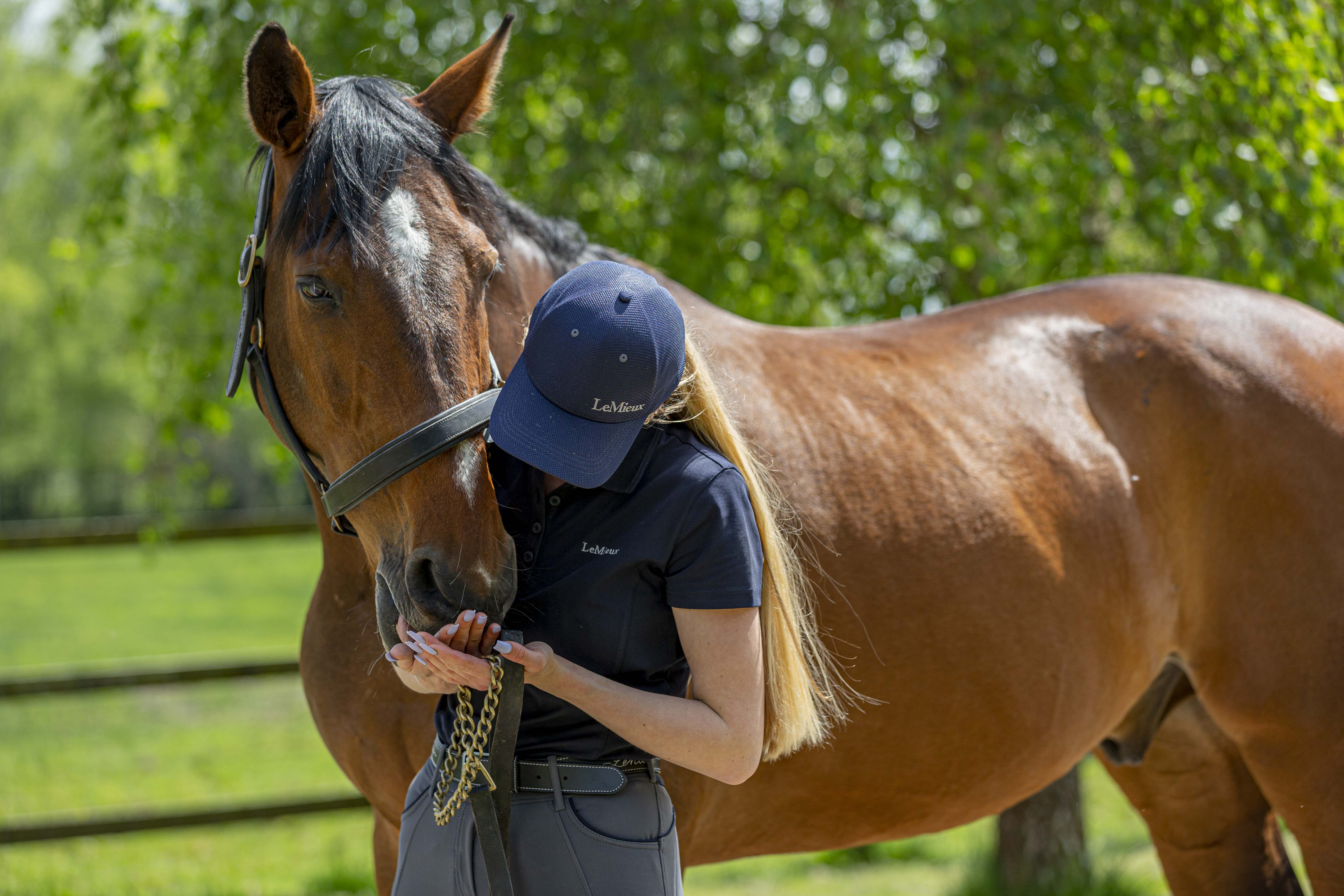 Bond with your horse. A women in a navy cap and t-shirt cuddles a bay horse