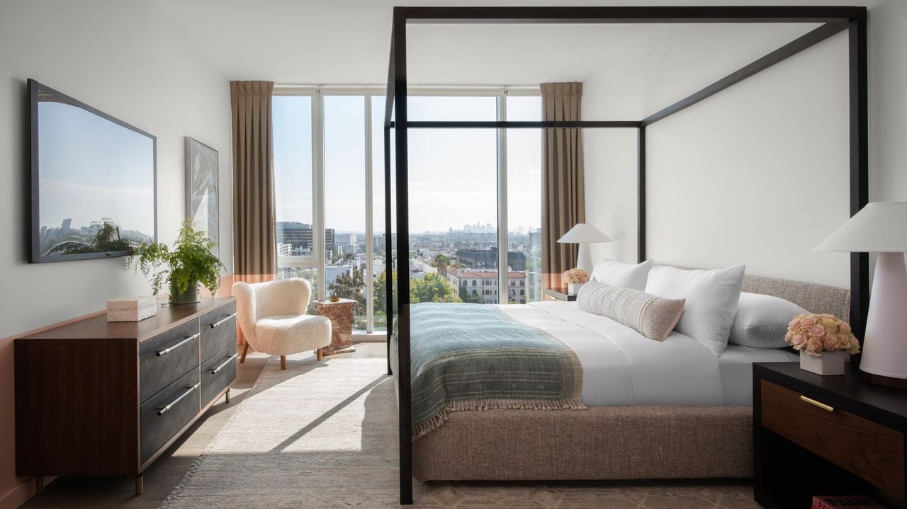 hotel bedroom with white walls, black four poster bed and large windows