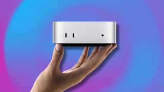 A hand holding up an M4 Mac mini in front of an abstract blue and purple background