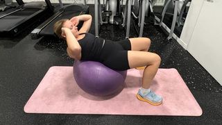 Woman performs gym ball crunch