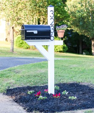 Flower bed mailbox landscaping ideas around a white and black mailbox.