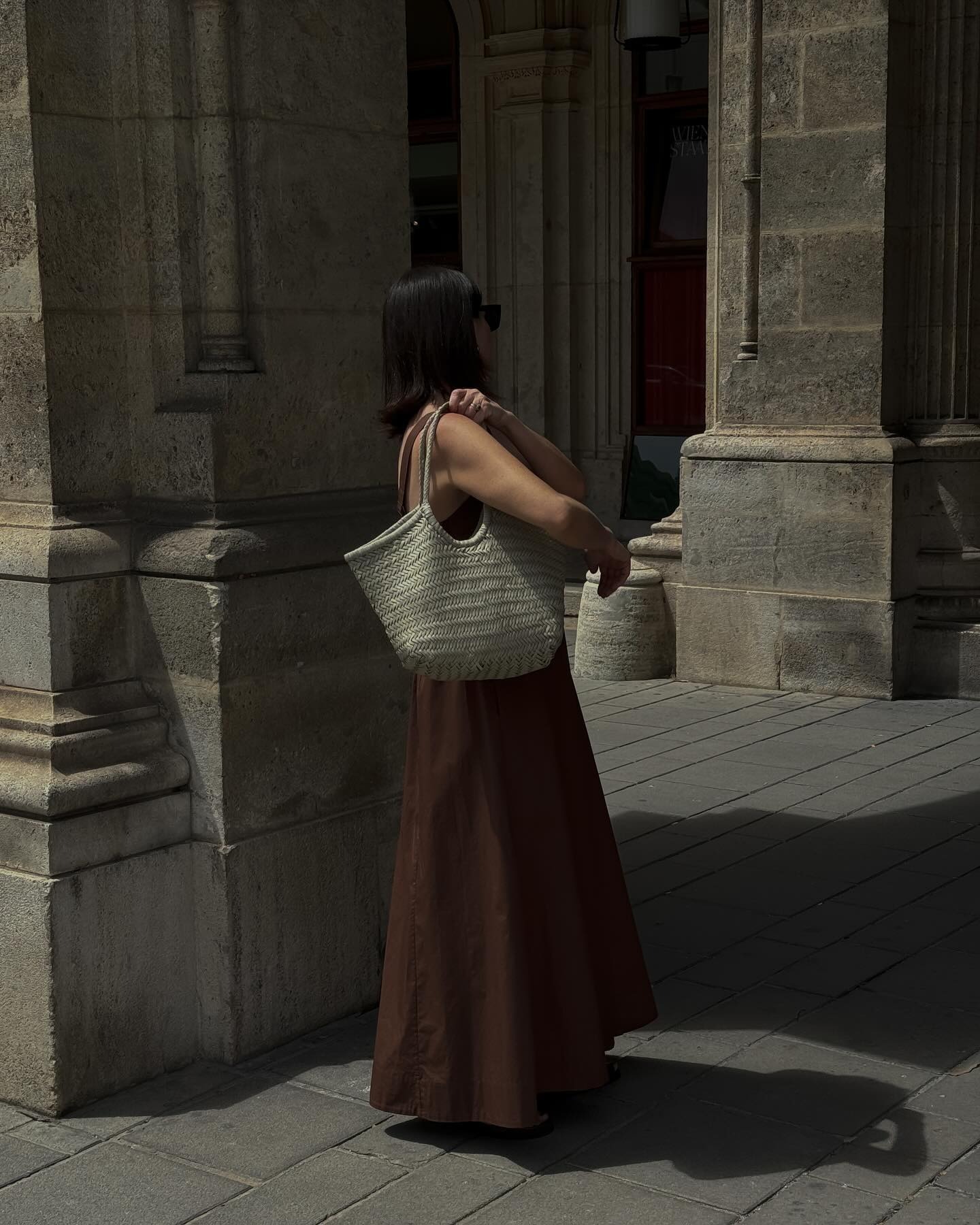 Woman wears brown dress, cream leather bag