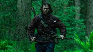 Aaron Taylor-Johnson runs in a forest with a bow on his back