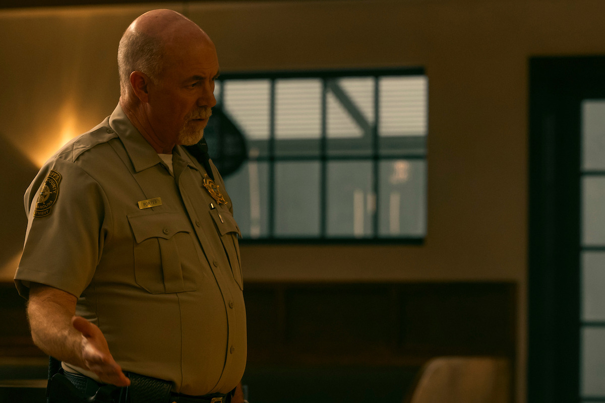 Michael Gaston as Sheriff Clyde Porter in his uniform at the police station in the waterfront