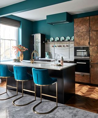 Designing a modern kitchen, in a turquoise scheme with herringbone wood flooring and a mix of metals and textures.