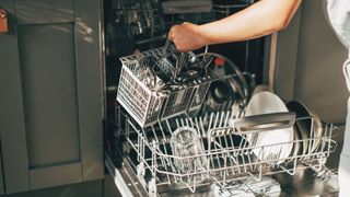 woman taking the cutlery compartment out of her dishwasher