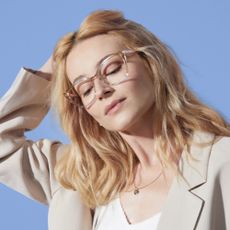 Model wearing see through framed glasses sold at Glasses Direct on a light blue background