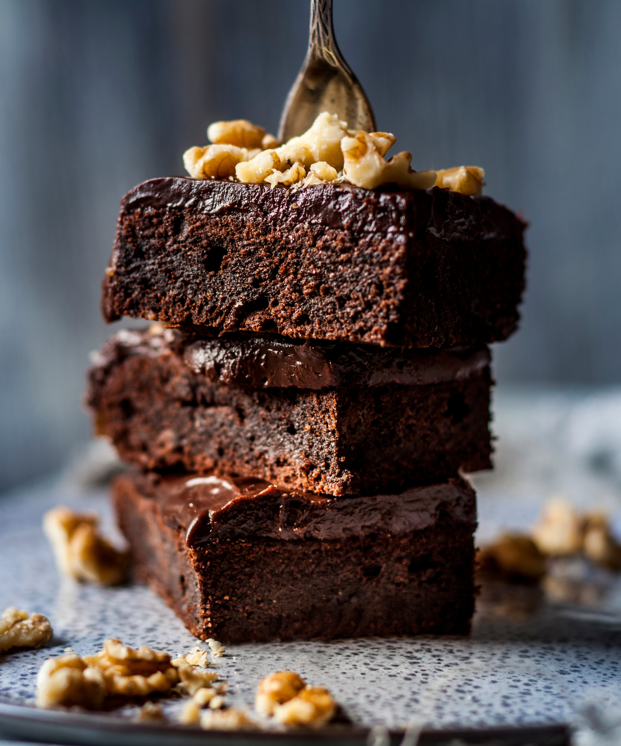 A tower of three chocolate brownies, garnished with chopped walnuts