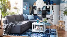 A blue living room with white open shelving used as room divider and white coffee table with caster wheels