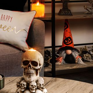 close up of skull decoration on a coffee table in a halloween themed living room, with a halloween gonk and other decorations on a display unit behind next to a couch