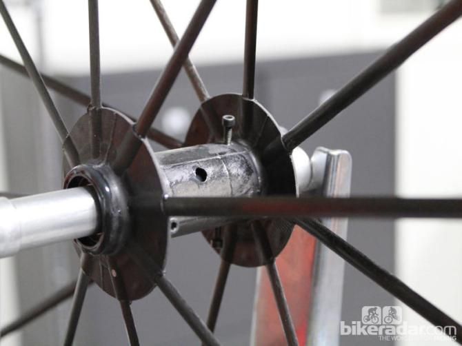 Finally, the wheel is trued using bolts that thread through the outer hub up against the inner, adjusting it like a Christmas tree in a stand. Then adhesive is poured into the hole and the two hubs and solidified