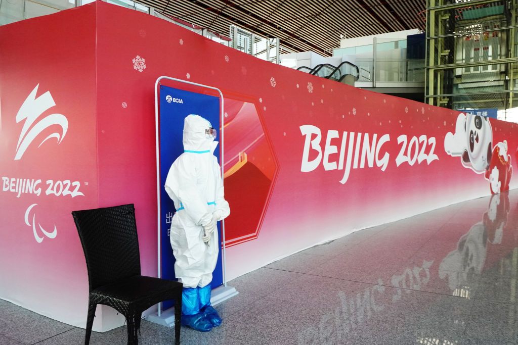 An image of a health worker standing in front of a Beijing 2022 sign