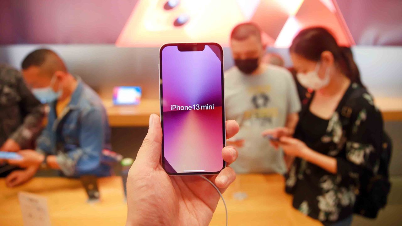 A person holds up an iPhone 13 Mini in a store. Apple announced record iPhone sales in its most recent quarter.