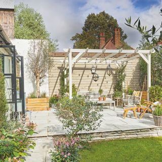 Outdoor patio area with wooden furntiure and a timber pergola