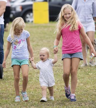 Savannah Phillips and Isla Phillips hold hands with Lena Tindall