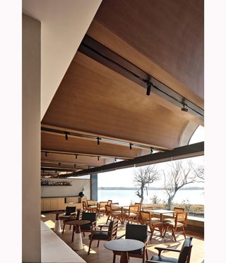 cafe-style seating on terrace beneath undulating roof at Boatyard hotel,