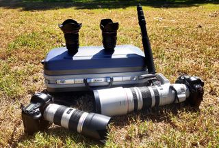 A camera kit on a hard case with two Canon bodies and four lenses