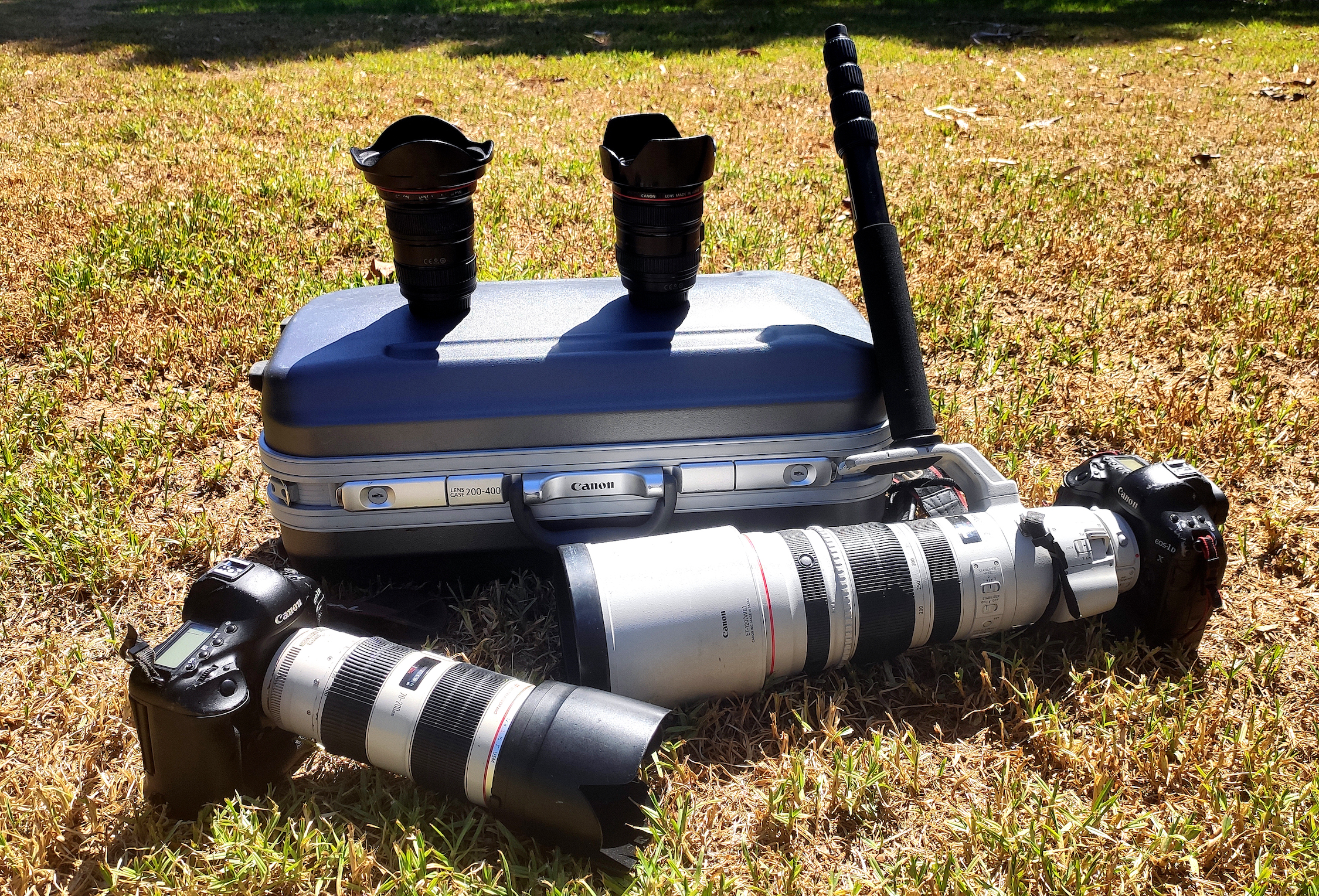 A camera kit on a hard case with two Canon bodies and four lenses