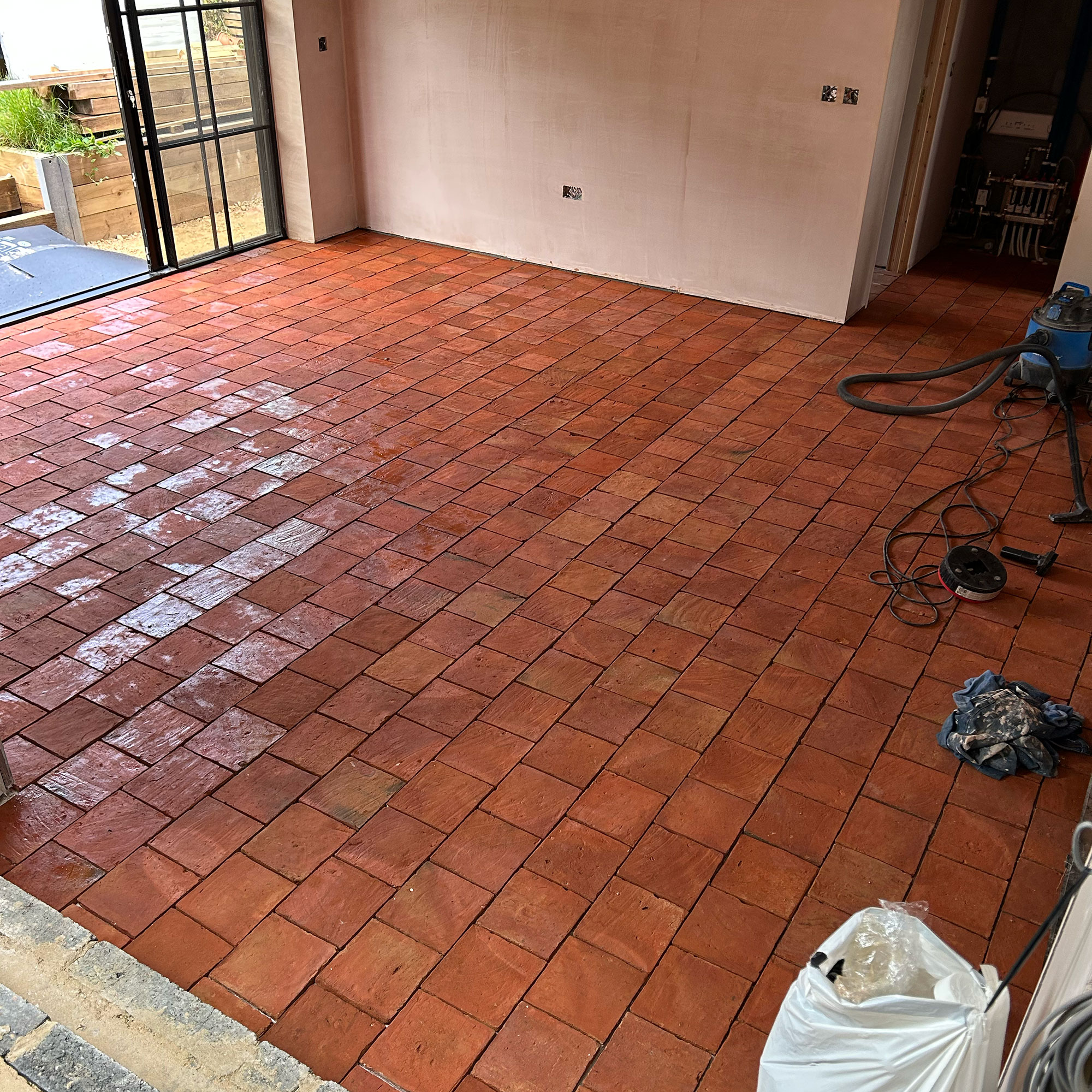 Empty room mid-renovation with bare walls and terracotta tiled floors