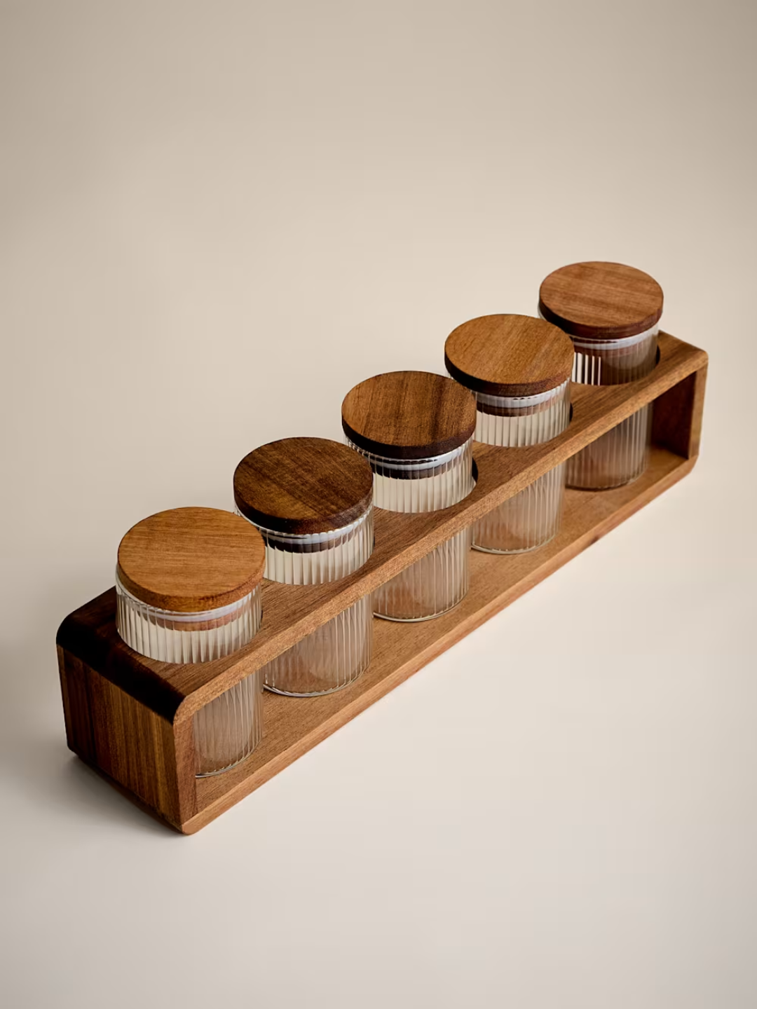 A wooden holder with five ribbed glass spice jars with lids from M&amp;amp;S